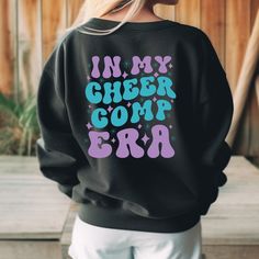 a woman wearing a black sweatshirt with the words in my cheer com era printed on it