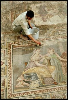 a man kneeling down next to a painting on the floor with a bucket in his hand