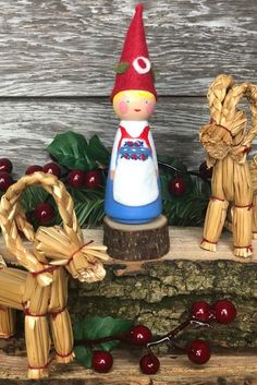 two small wooden figurines sitting next to each other on a tree stump with cherries around them