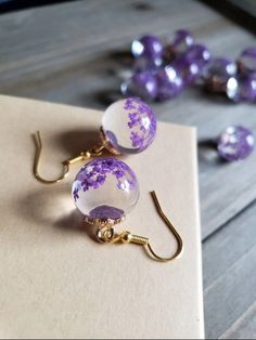 Elegant spring flowers in glass orbs. Warm gold metal fastenings, and gold plated earring hooks. Beautifully elegant, with delicate and finely detailed flowers. Colorful real dried flowers in every perfected glass orb.  Bold and luxurious violet PURPLE, the floral royalty, and color of spirituality. The fierce depth of the wild violet flower comes from the energy of red combined with calm of blue. Symbolizing combined feelings, and complex emotions, violet color inspires reflection and self awar Dried Flower Jewelry, Coat Pocket, Bridesmaid Gifts Jewelry, Meaningful Messages, Violet Flower, Burlap Ribbon, Colorful Jewelry, Unique Flowers, Glass Ball