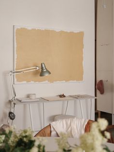 a room with a table, chair and lamp next to a painting on the wall