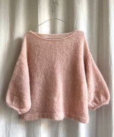 a pink sweater hanging on a white curtain