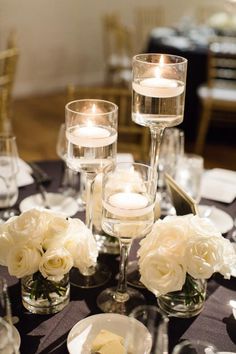 the centerpieces are filled with white roses and candles for an elegant table setting