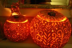 two decorative pumpkins lit up in the dark with lights on them and a mirror behind them