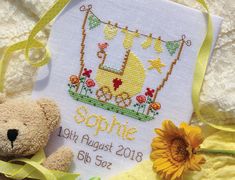 a cross stitch baby's birth card with a teddy bear and sunflowers