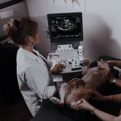 two women in white lab coats are holding kittens and looking at an x - ray