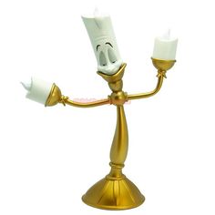 a gold colored candle holder with two white candles on it's arms and legs