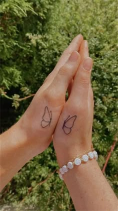 two people holding hands with small tattoos on them