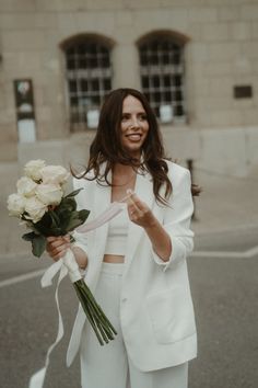 a woman in white is holding flowers and smiling