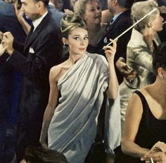 a woman standing in front of a crowd holding an umbrella