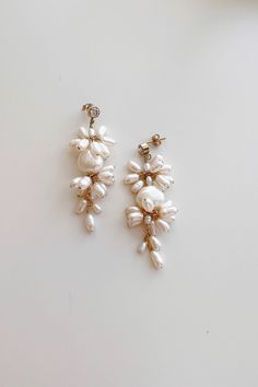 two pairs of earrings with pearls hanging from the end of each earring, on a white surface