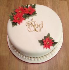 a white cake decorated with poinsettis and the word joy