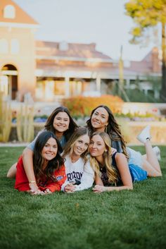 a group of young women laying on top of a lush green field next to each other