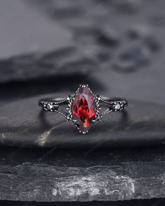 a red stone ring sitting on top of a rock