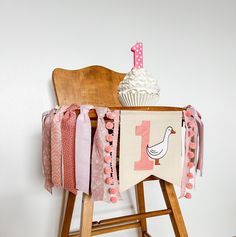 a wooden chair with a cupcake on top of it next to a birthday banner