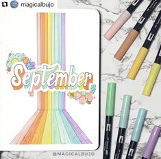 some markers and pens are sitting on a marble surface with the word september written in rainbow colors