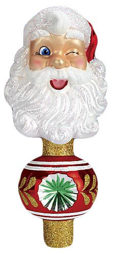 a glass santa clause ornament on top of a red and white vase with gold trim