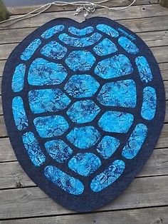 a blue turtle shell shaped rug sitting on top of a wooden floor next to a fence