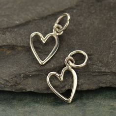 Sterling Silver Small Open Heart Charm. This tiny heart charm is made of half hammered wire so one half is hammered flat. It also has been designed with the jump ring off center so the heart sits to the side! Wear it alone or in a collection of other charms for a fun, flirty look. Length measure includes 5 mm jump ring: 14 mm x 7 mm Open Heart Ring, Silver Heart Ring, Monogram Jewelry, One Half, Silver Charm Bracelet, Tiny Heart, Charm Pendant Necklace, Open Heart, Birthstone Charms