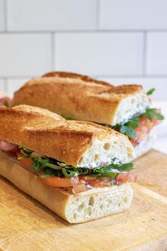 two halves of a sandwich sitting on top of a cutting board next to each other