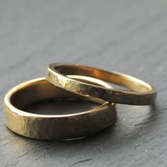 two gold wedding rings sitting side by side on a gray surface with no one in the photo