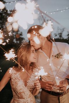 a man and woman standing next to each other holding sparklers