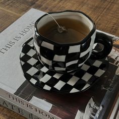 a black and white checkered tea cup sitting on top of a book