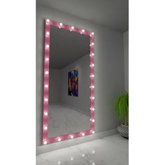 a large mirror with lights on it in a room next to a potted plant