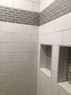 a bathroom with white subway tile and gray grouting on the walls, along with two windows