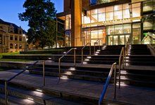 stairs leading up to a building at night with lights shining on the steps and windows