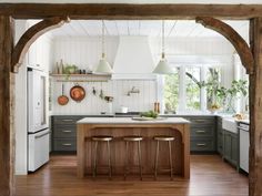 an open kitchen with two stools in front of the island and wooden beams on the ceiling