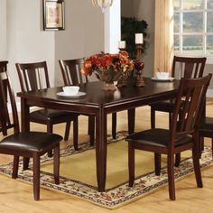 a dining room table and chairs with a rug on the floor