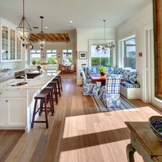 a large open concept kitchen and living room with hardwood floors, white walls, and wood flooring