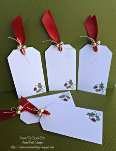 four white tags with red bows and holly on them