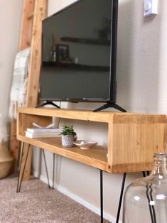 a flat screen tv sitting on top of a wooden shelf next to a glass bottle