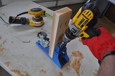 a person using a power drill to attach a piece of wood on top of a workbench