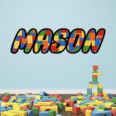 the word mason spelled out in lego letters over a pile of colorful plastic blocks on top of a wooden floor