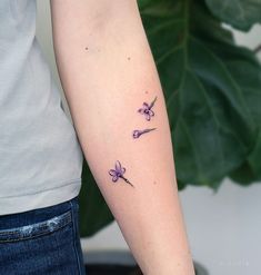 a woman's arm with three small flowers on the left side of her arm