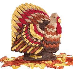 a crocheted turkey sitting on top of leaves in front of a white background