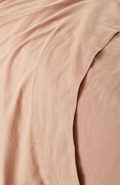 an unmade bed with pink sheets and pillows