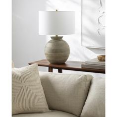 a white lamp sitting on top of a table next to a couch in a living room