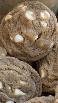 a pile of cookies sitting on top of each other next to a glass bowl filled with white chocolate chips