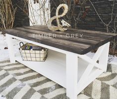 a white bench sitting on top of a rug next to a brick wall with the word timber and grey written across it