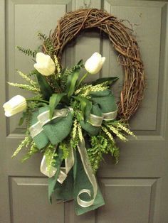 a wreath with white flowers hanging on a door