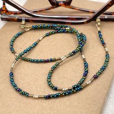 Shiny and bohemian eyeglass necklace chain in blue, purple, greenish and gold tones, made with Preciosa Czech crystal seed beads and gold plated crystal seed beads     Paired with beautiful gold plated crystal seed beads , this handmade eyeglass chain will definitely create a unique look. This eyeglass lanyard is made on strong quality beading wire with gold plated wire guardians that protect the quality white eyeglass holder grips. FREE Shipping for additional items  ~ All items are beautifully Gold Glasses Chains With Colorful Glass Beads, Bohemian Gold Glasses Chains With Colorful Beads, Green Bohemian Glasses Chains As Gift, Gold Glasses Chains With Round Beads For Festivals, Bohemian Beaded Gold Glasses Chains, Bohemian Green Glass Glasses Chains, Bohemian Gold Beaded Glasses Chains, Glasses Holder Necklace, Eyeglass Jewelry