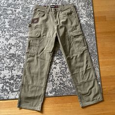 Wrangler Riggs Workwear Pants ‘Ranger’ Style, Relaxed Fit Green Side Pockets That Snap Button Carpenter Hammer Loop Heavy Duty Canvas Make ‘Rip Stop’ Design Seem Impossible To Tear 31 X 30 Tag Says 32 X 30 But They Measure Tighter See Photo For Measurement 15.75” Left To Right Waist 9” Leg Opening Brand New Item With Tags Same Day Shipping Rugged Cotton Bottoms With Hip Pockets, Rugged Cotton Jeans With Belt Loops, Outdoor Full-length Cotton Jeans, Rugged Cotton Bottoms With Standard Cut Leg, Outdoor Jeans With Straight Leg And Belt Loops, Rugged Straight Leg Bottoms With Patch Pockets, Rugged Outdoor Cotton Jeans, Rugged Cotton Jeans With Pockets, Construction Pants