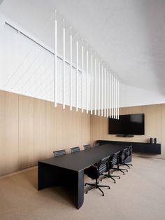 an empty conference room with black chairs and a flat screen tv mounted on the wall