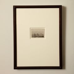 a framed photograph of a boat on the water in black and white with a brown frame