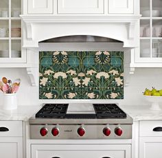 a stove top oven sitting inside of a kitchen next to white cabinets and counter tops