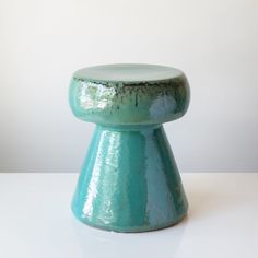 a small blue stool sitting on top of a white table next to a wall and floor